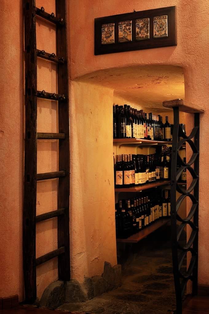 La cantina dell'Osteria da Nando: bottiglie negli scaffali sotto la volta in pietra