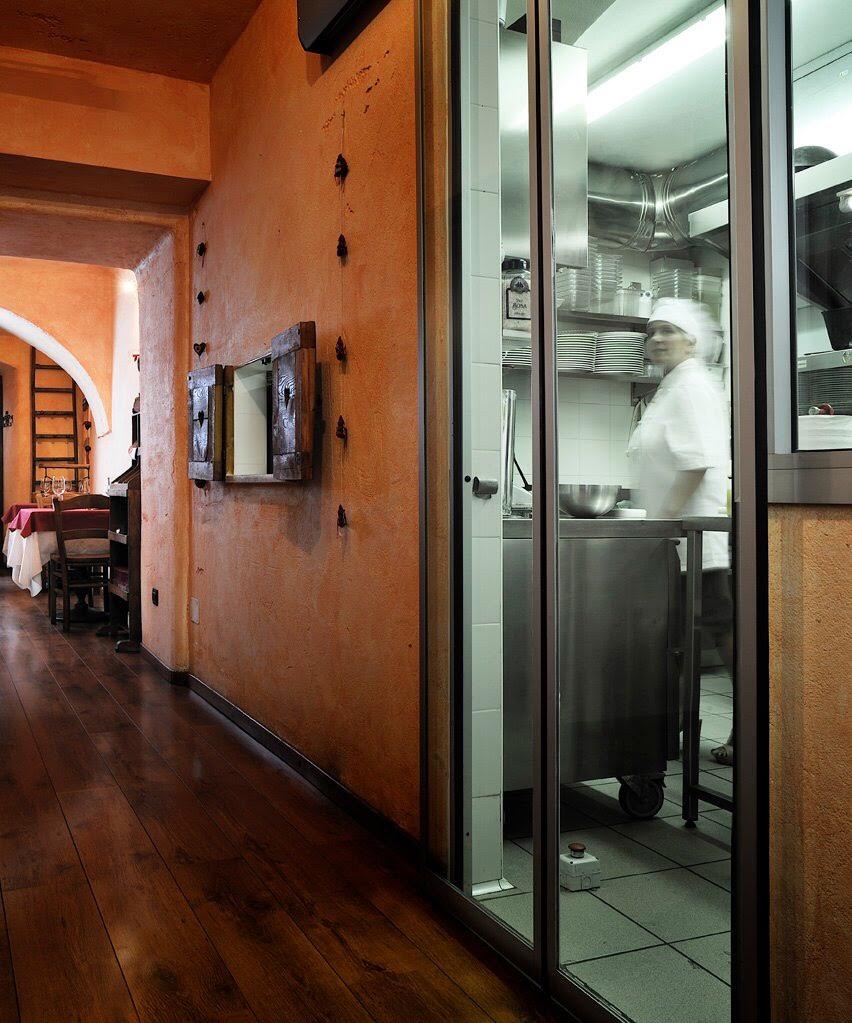 La cucina dell'Osteria da Nando vista dal corridoio, dietro la vetrata